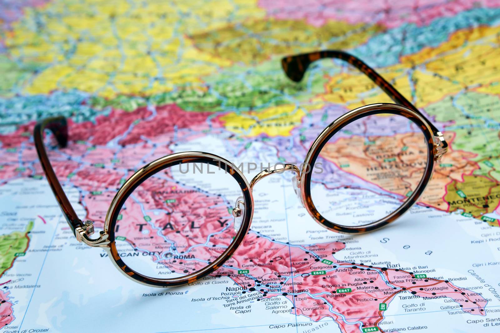 Photo of glasses on a map of europe. Focus on Italy. May be used as illustration for traveling theme.