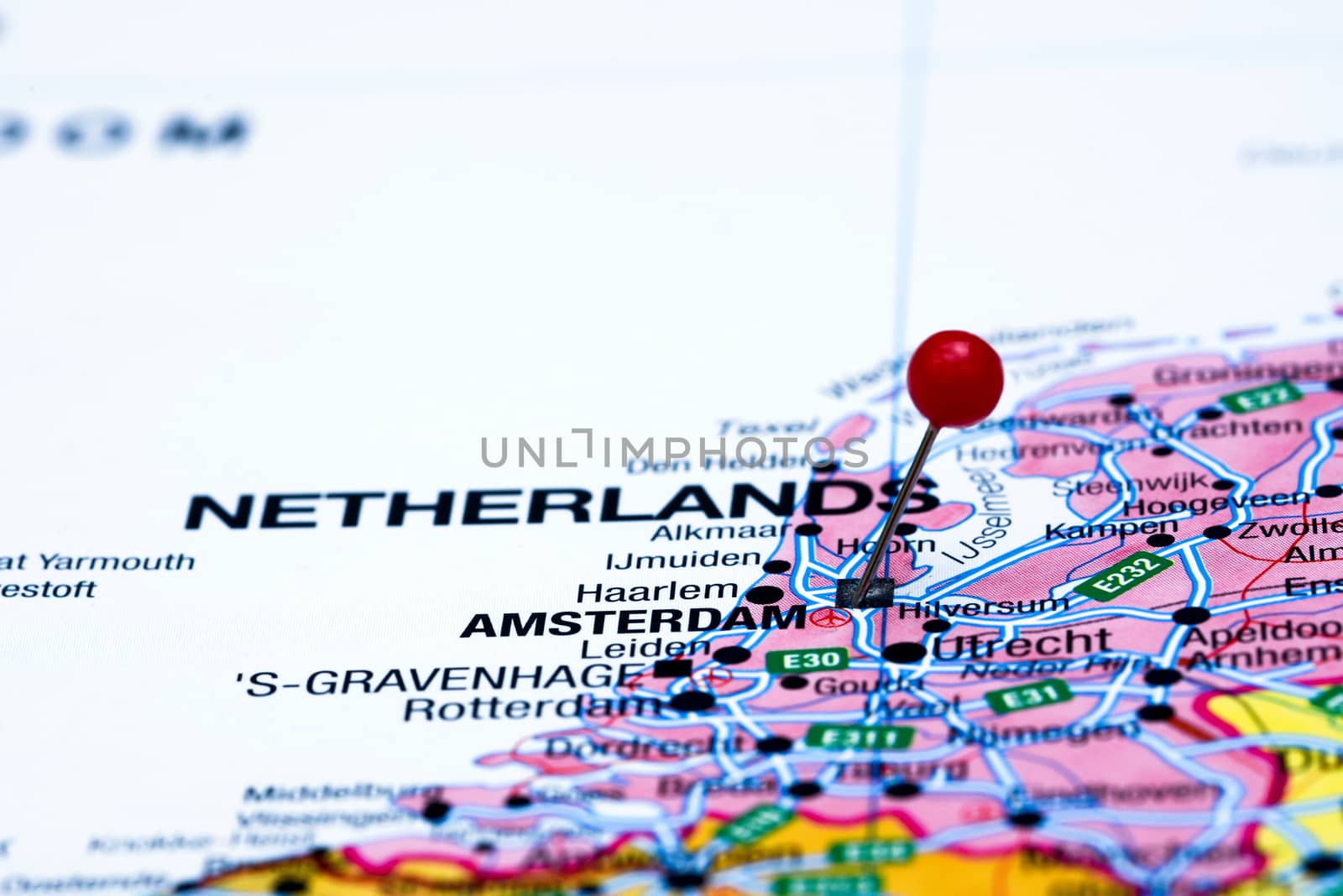 Photo of pinned Amsterdam on a map of europe. May be used as illustration for traveling theme.