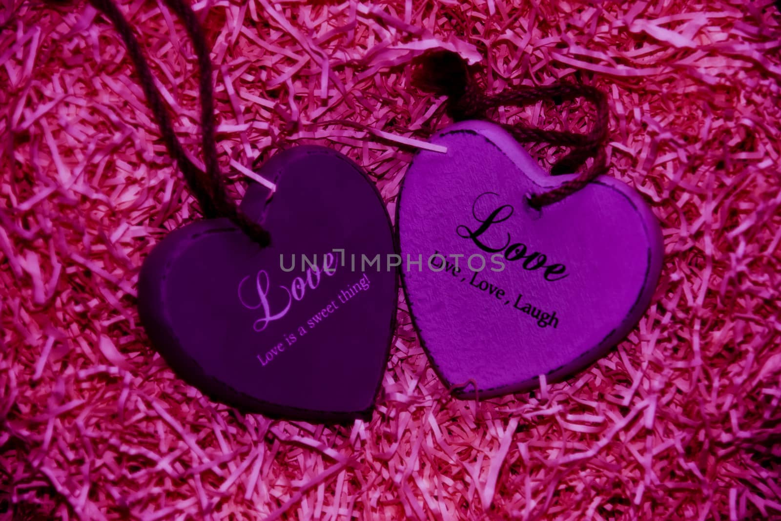 two pink wooden love hearts in a love nest made of straw with loving inscriptions