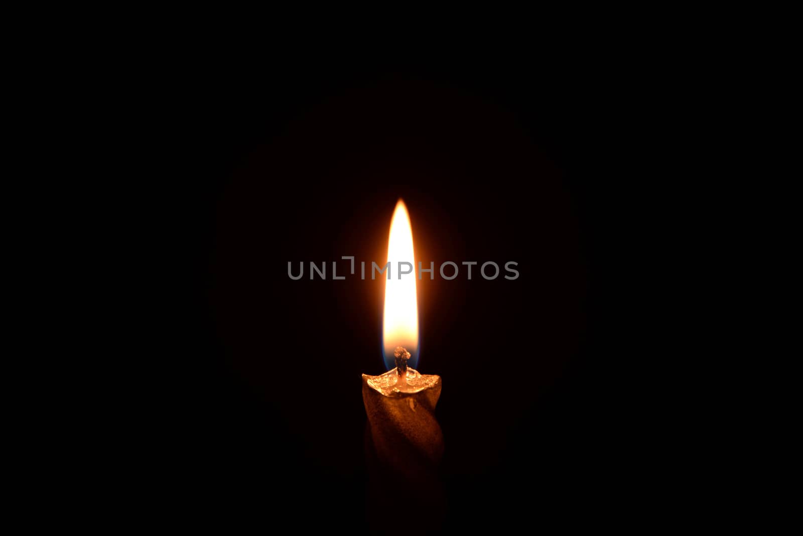 Photo of a silver candle burning on a black background.