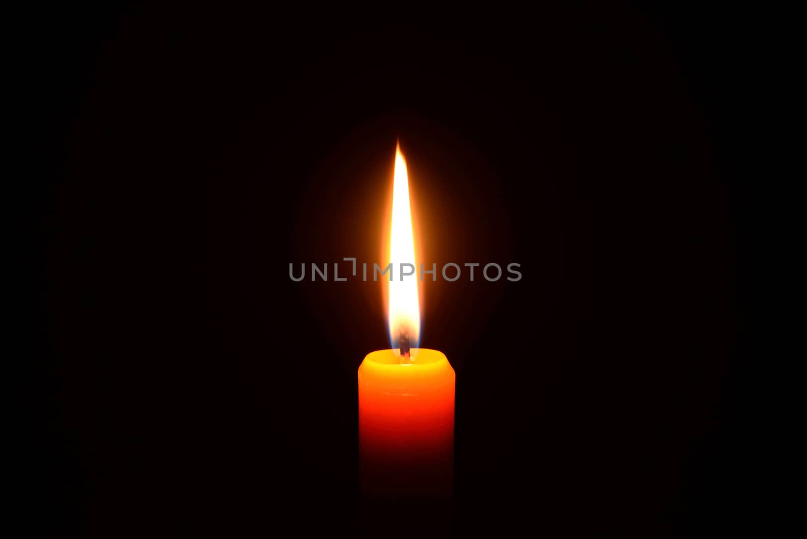 Photo of an orange candle burning on a black background.