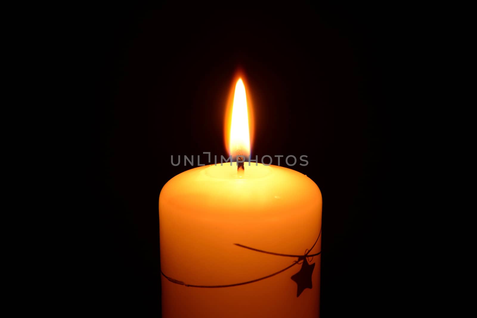 Photo of a white christmas candle burning on a black background.