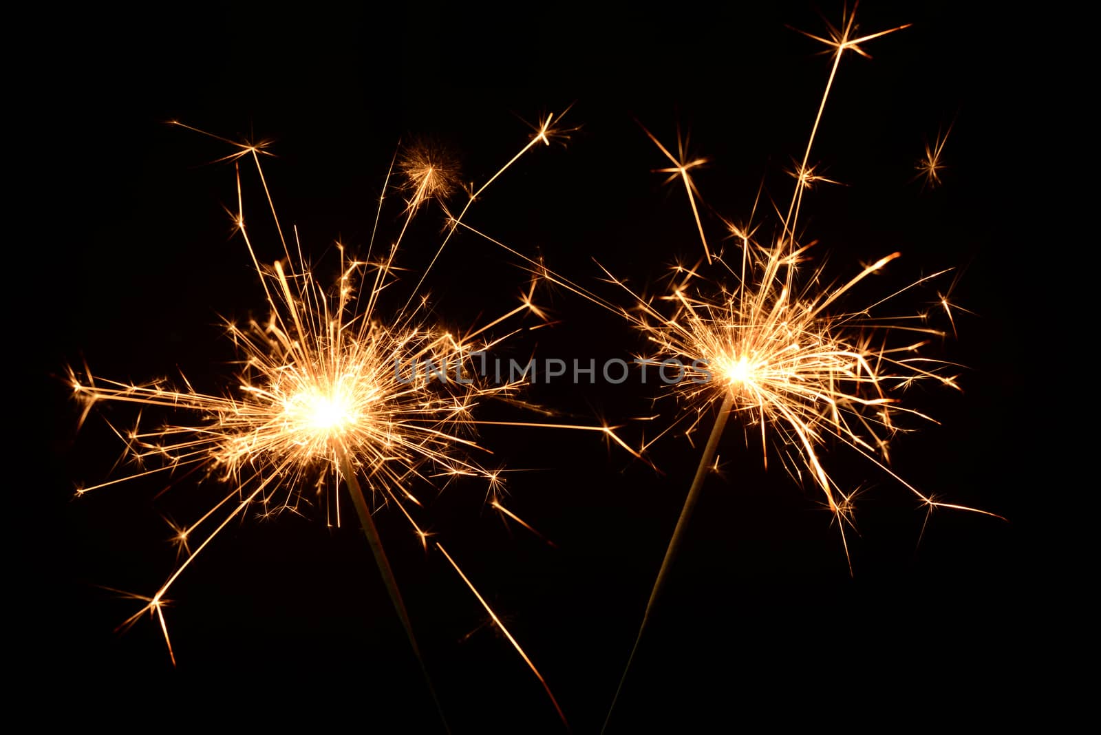 Photo of two burning christmas sparklers on a black background