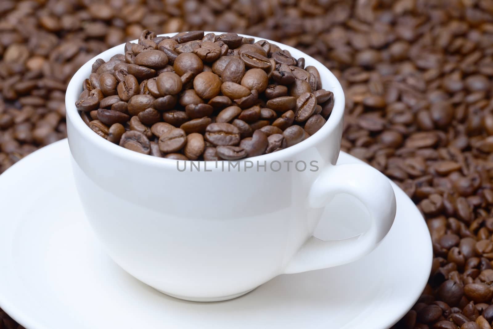 Photo of a cup of coffee with coffee grains on a saucer. White color cup on a brown coffee beans background. Food photography.