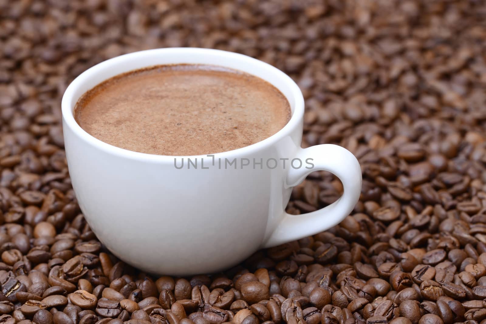 Photo of a white color cup on a brown coffee beans background. Food photography.
