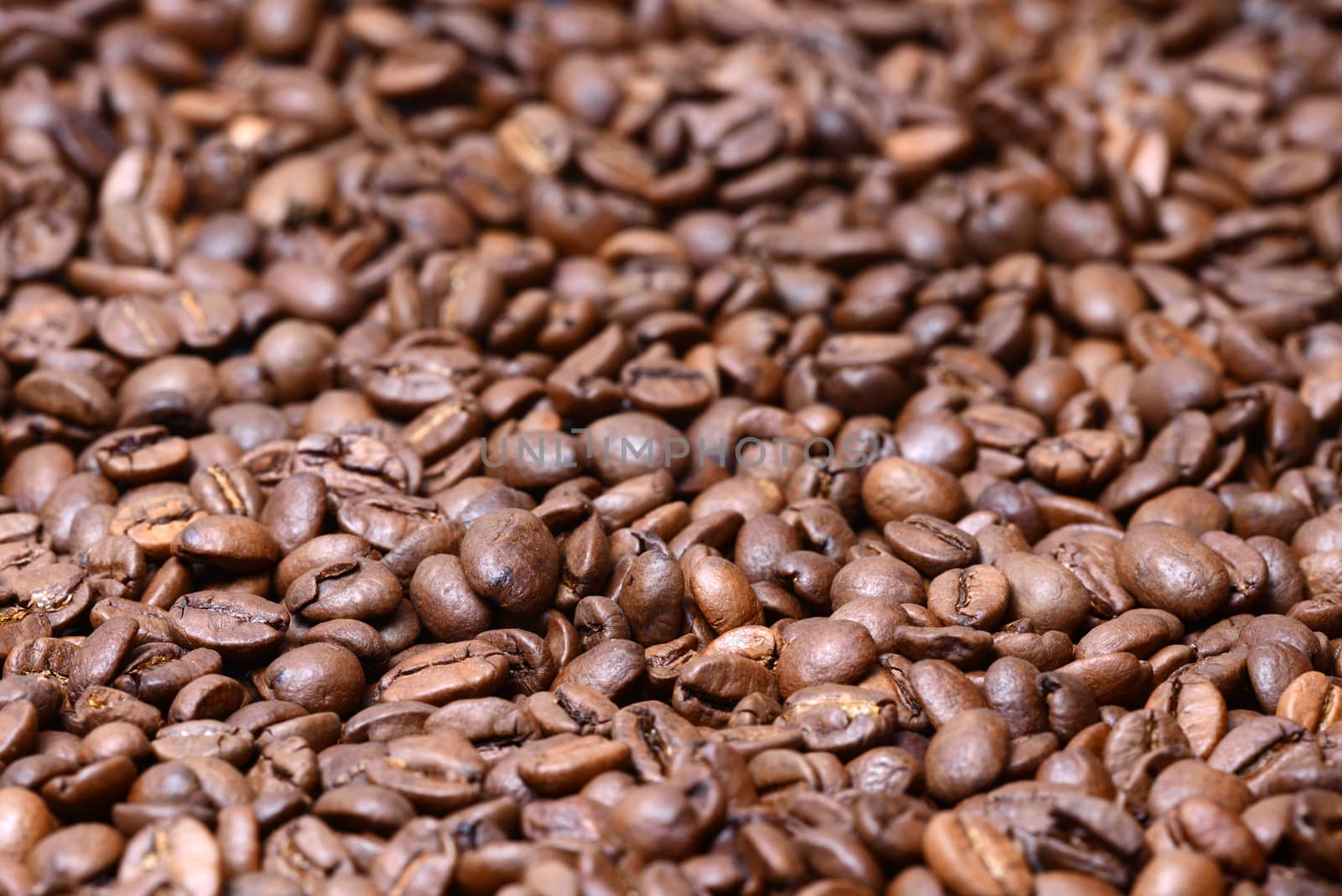 Photo of a heap of brown coffee beans. May be used for for background and texture. Food photography.
