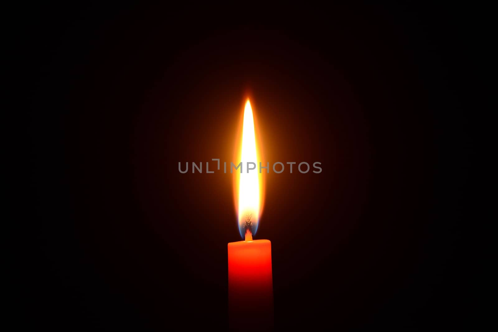 Photo of an red candle burning on a black background.