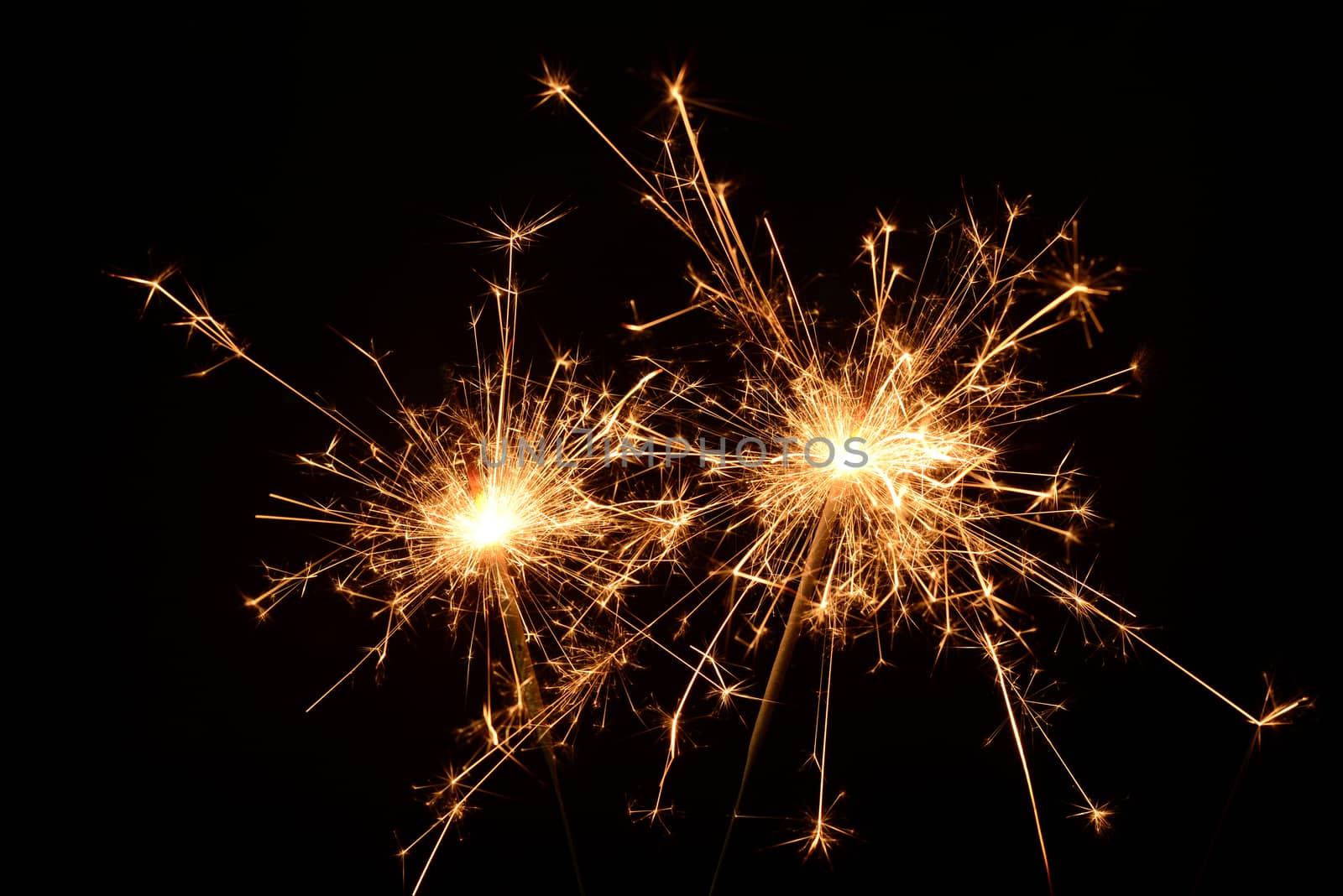 Photo of two burning christmas sparklers on a black background