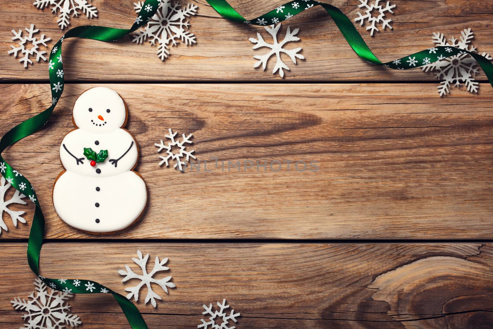 Christmas background with gingerbread cookie in shape of snowman on wooden table. Copy space. Top view