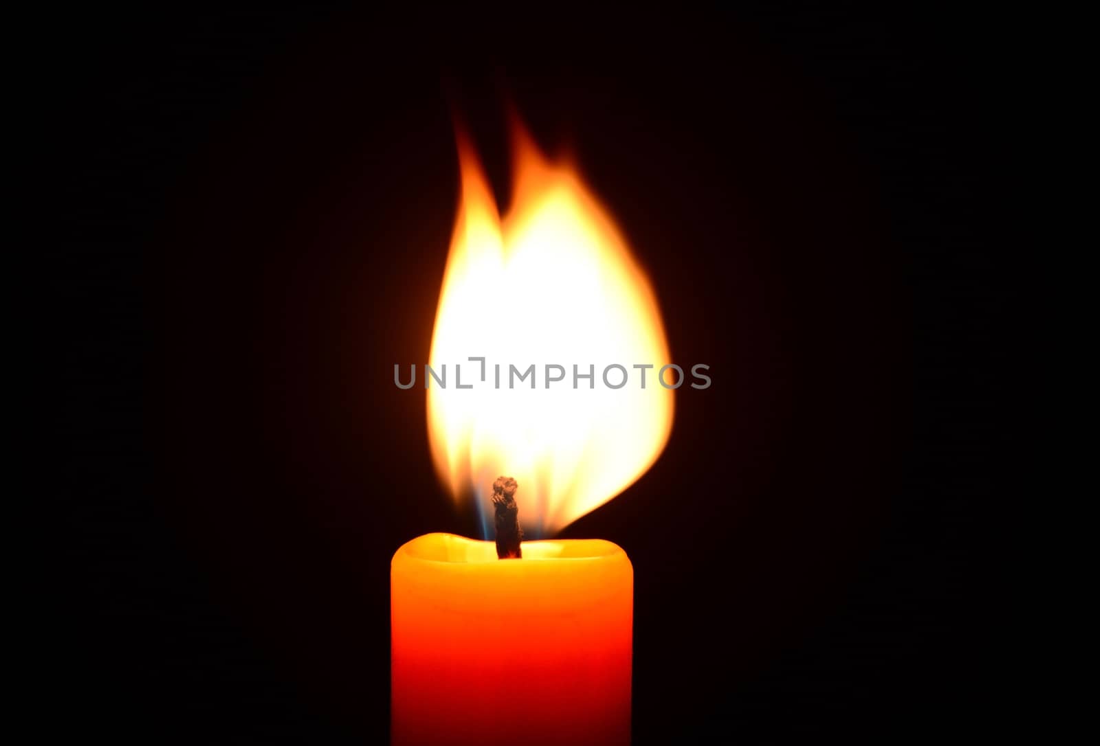 Orange candle burning on a black background by dk_photos