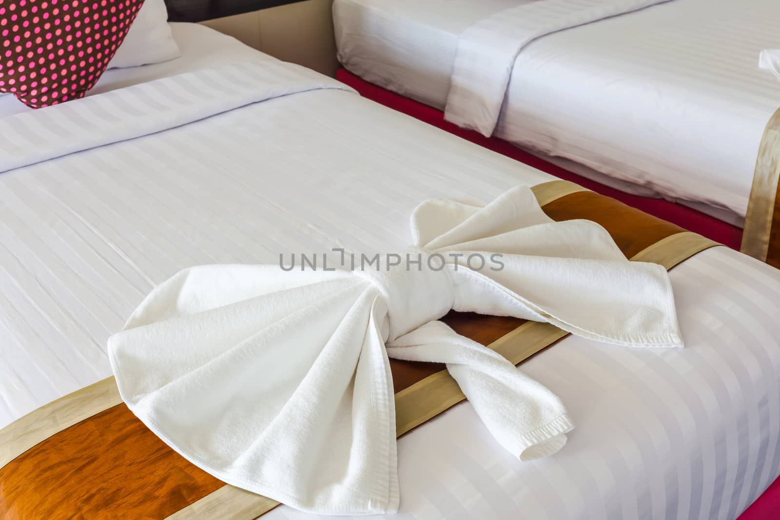 White Towel folded in bow shape on bed by FrameAngel