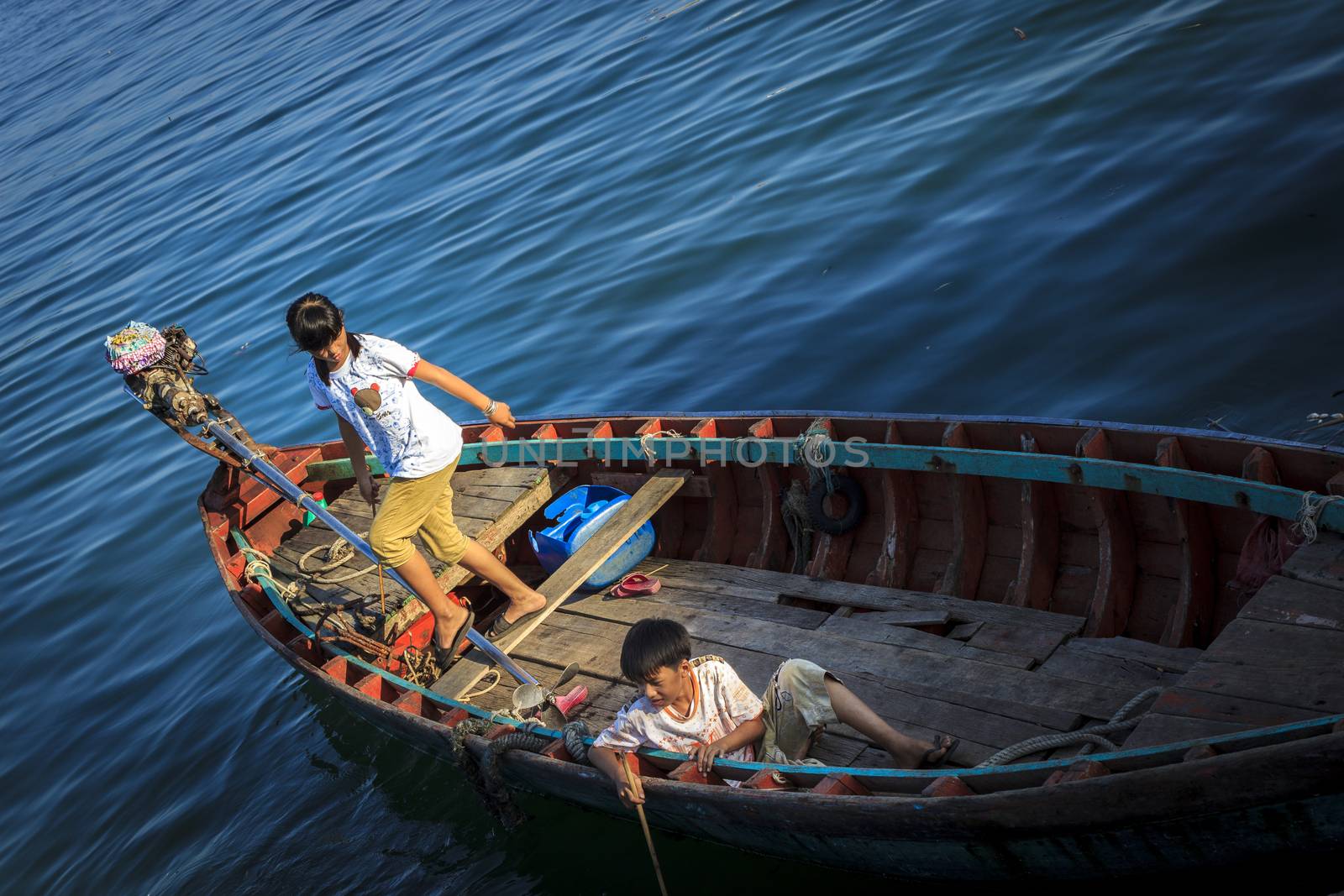 Phu Quoc, Vietnam - November 2nd, 2013: At the sunset, two childs were playing very fun in their boat in An Thoi fishing harbor, Phu Quoc, Vietnam