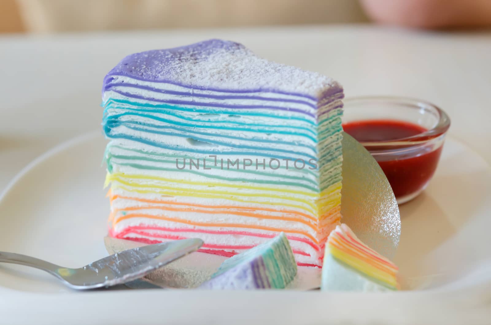 Rainbow crepe cake served with strawberry sauce