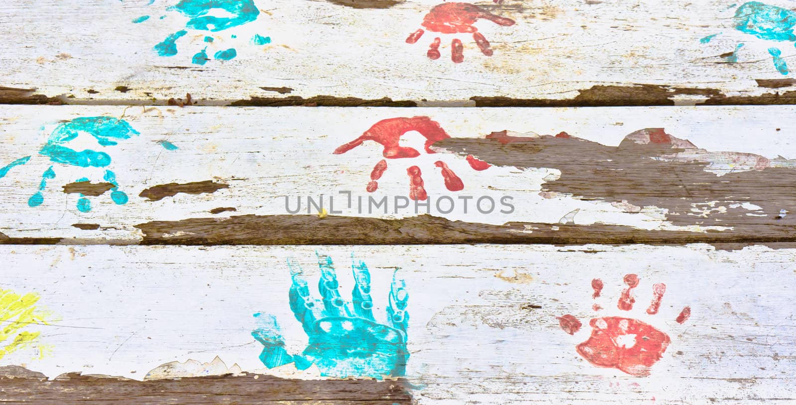 Hand prints in red and blue paint on a white wooden surface