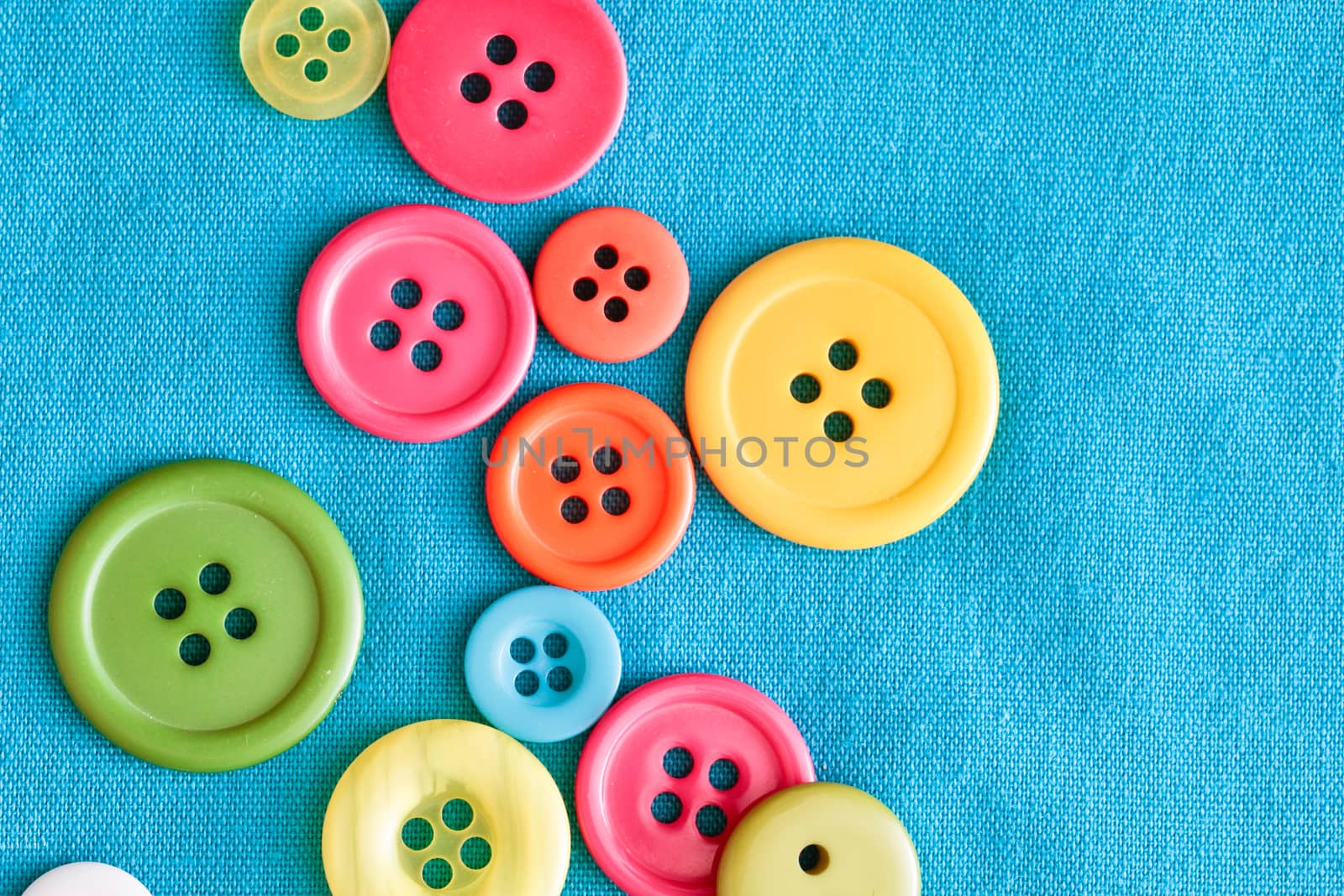 Colorful plastic buttons on blue textile, as a background image