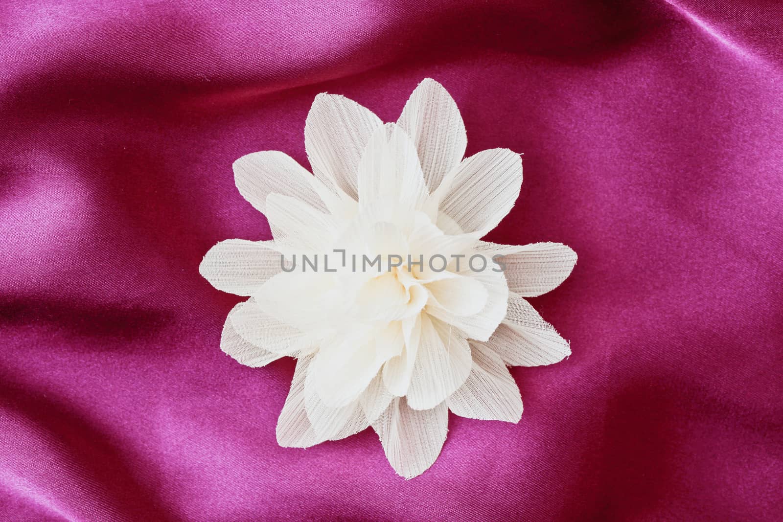 A fabric flower on a purple sheet