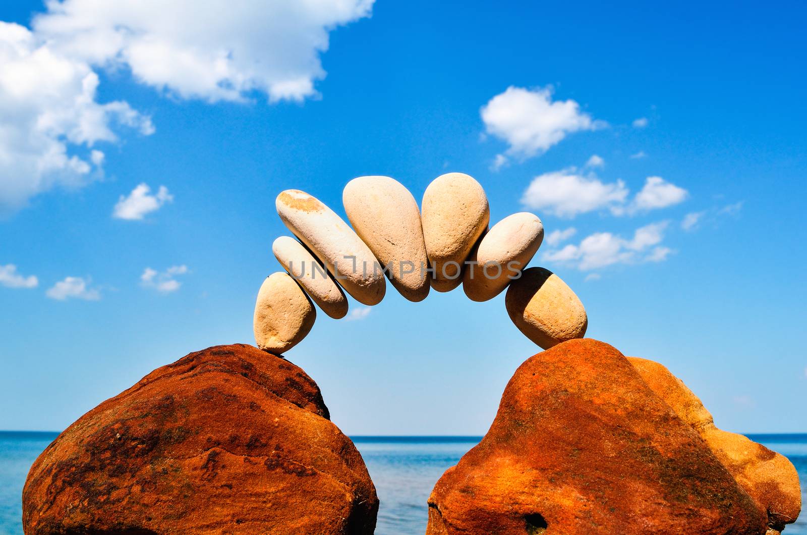 Curve of pebbles between of the red stones on the seashore