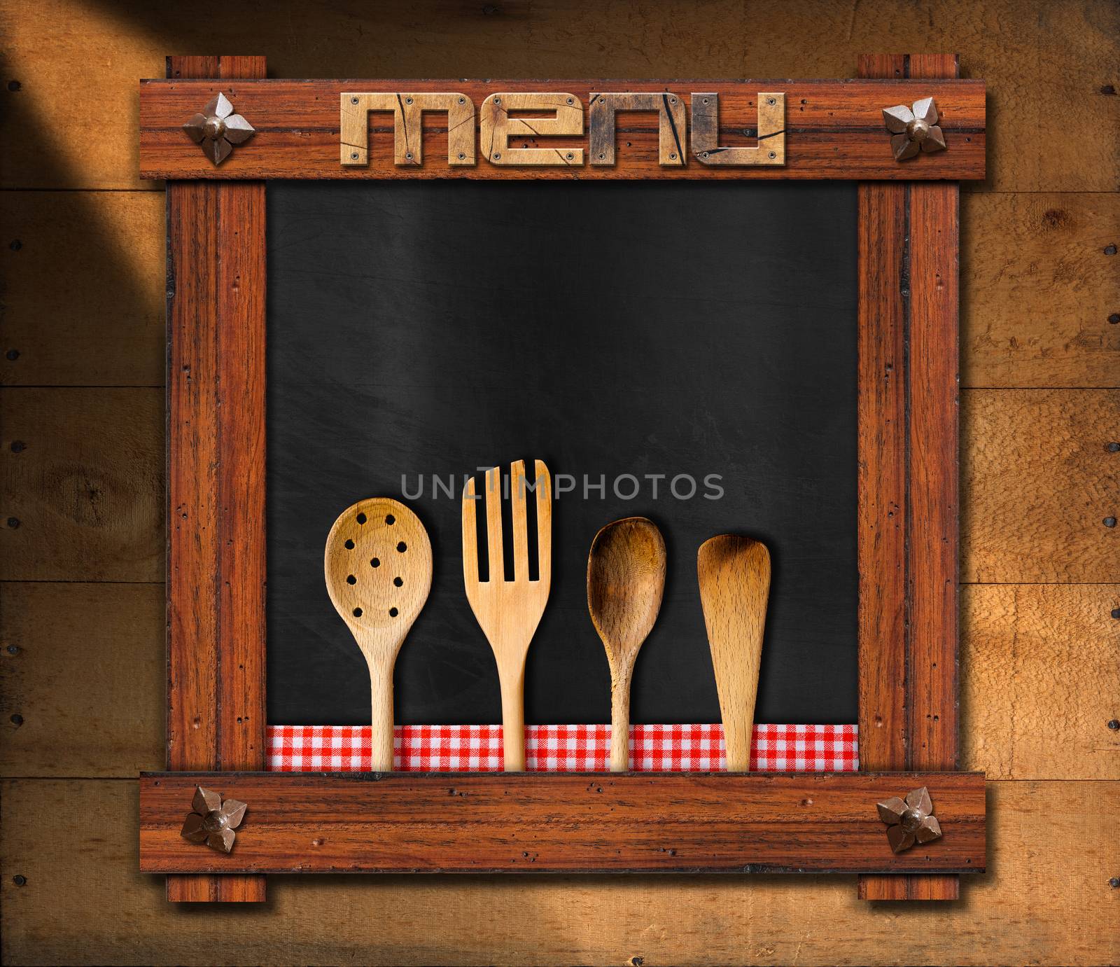 Empty blackboard with wooden frame, ancient nails and wooden written menu, four wooden kitchen utensils with red and white checkered tablecloth on wooden background