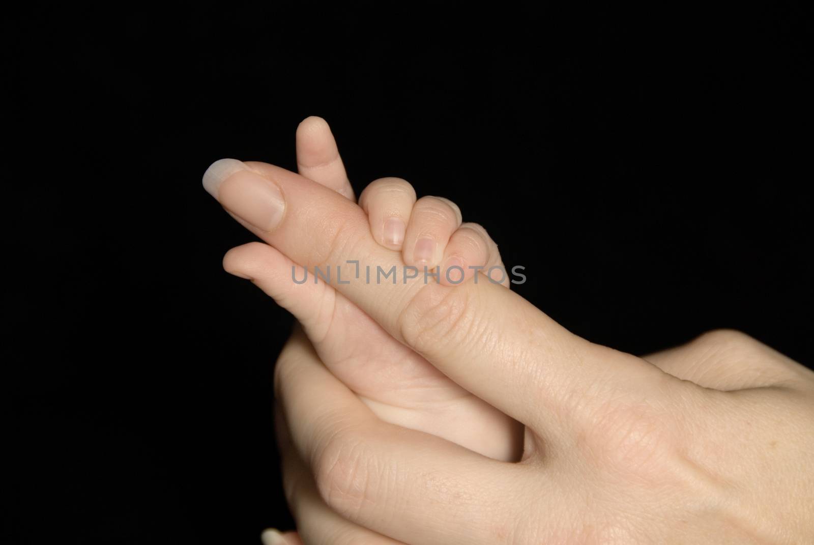 Five week old baby holding mothers finger.