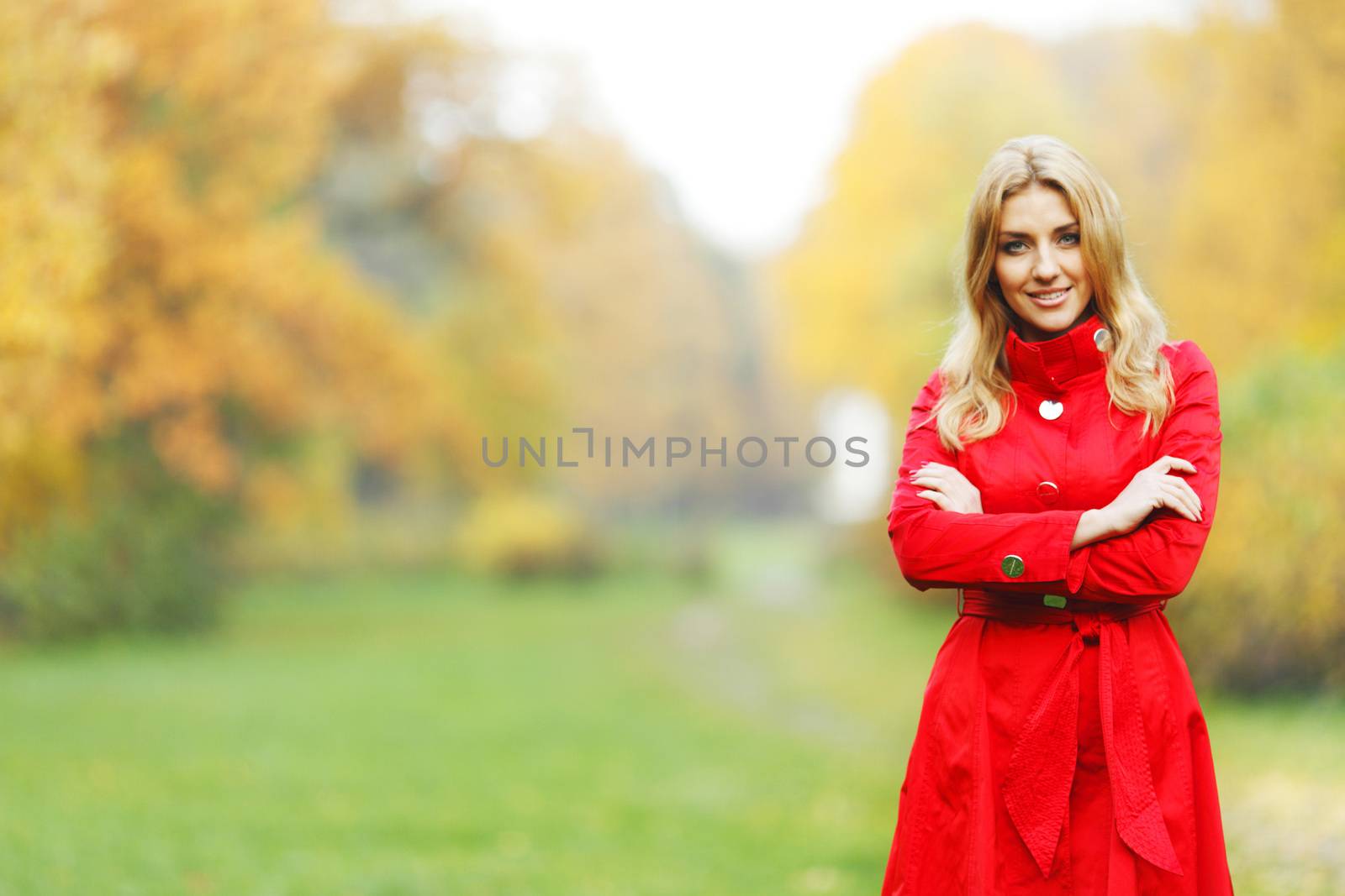 Young woman in red coat walking in autumn park