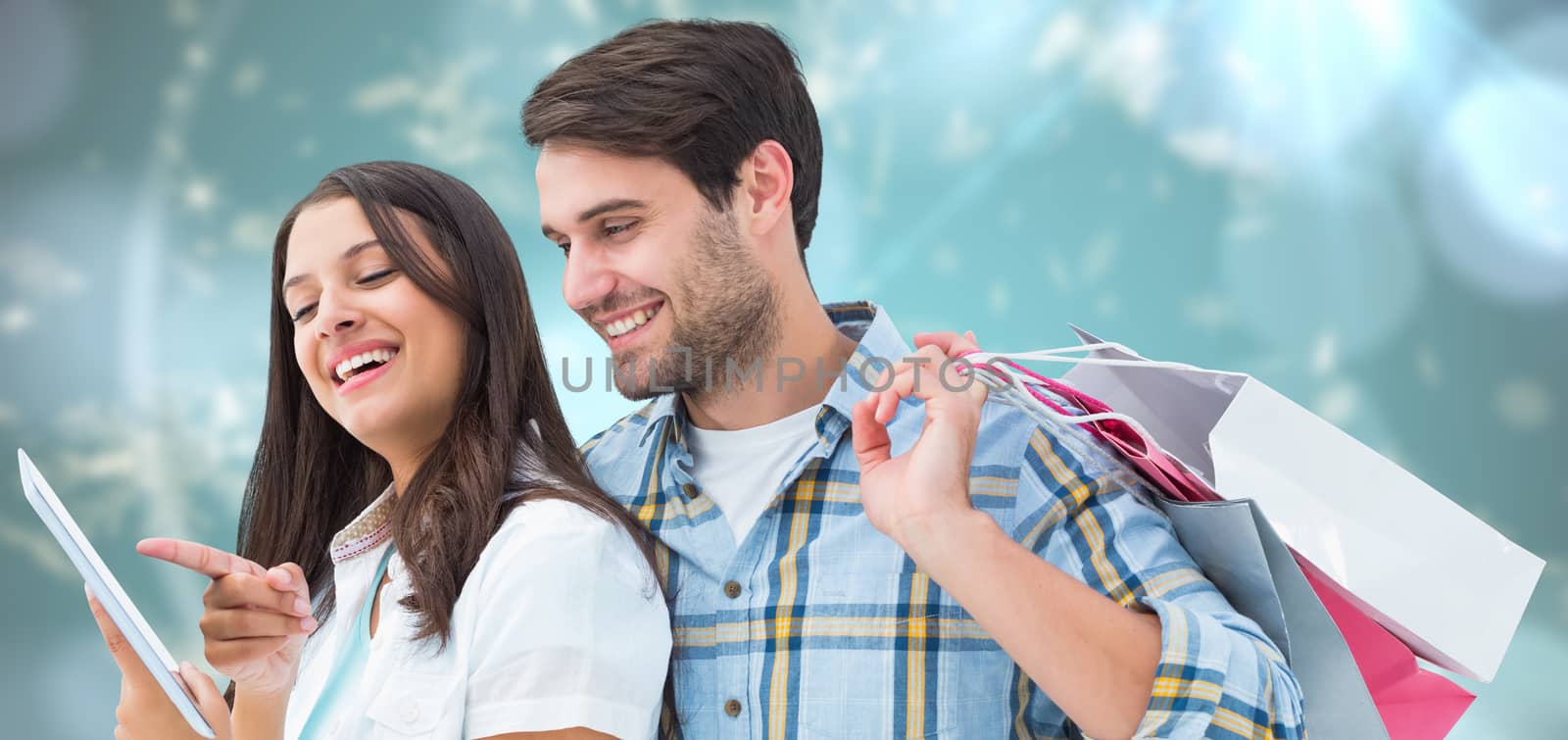 Happy couple with shopping bags and tablet against blurred christmas background