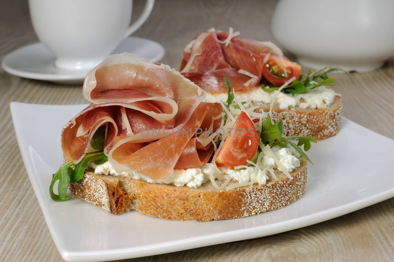 Sandwich of jamon with ricotta, arugula, cheese and a slice of cherry