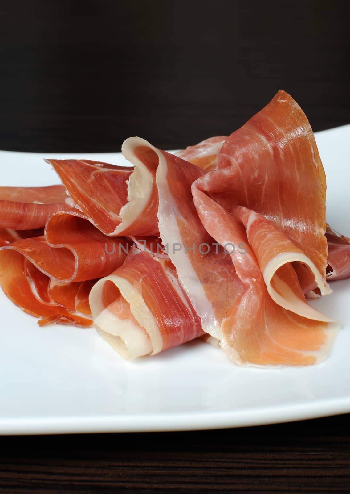 Uncooked jerked pork ham slices of jamon on a white plate