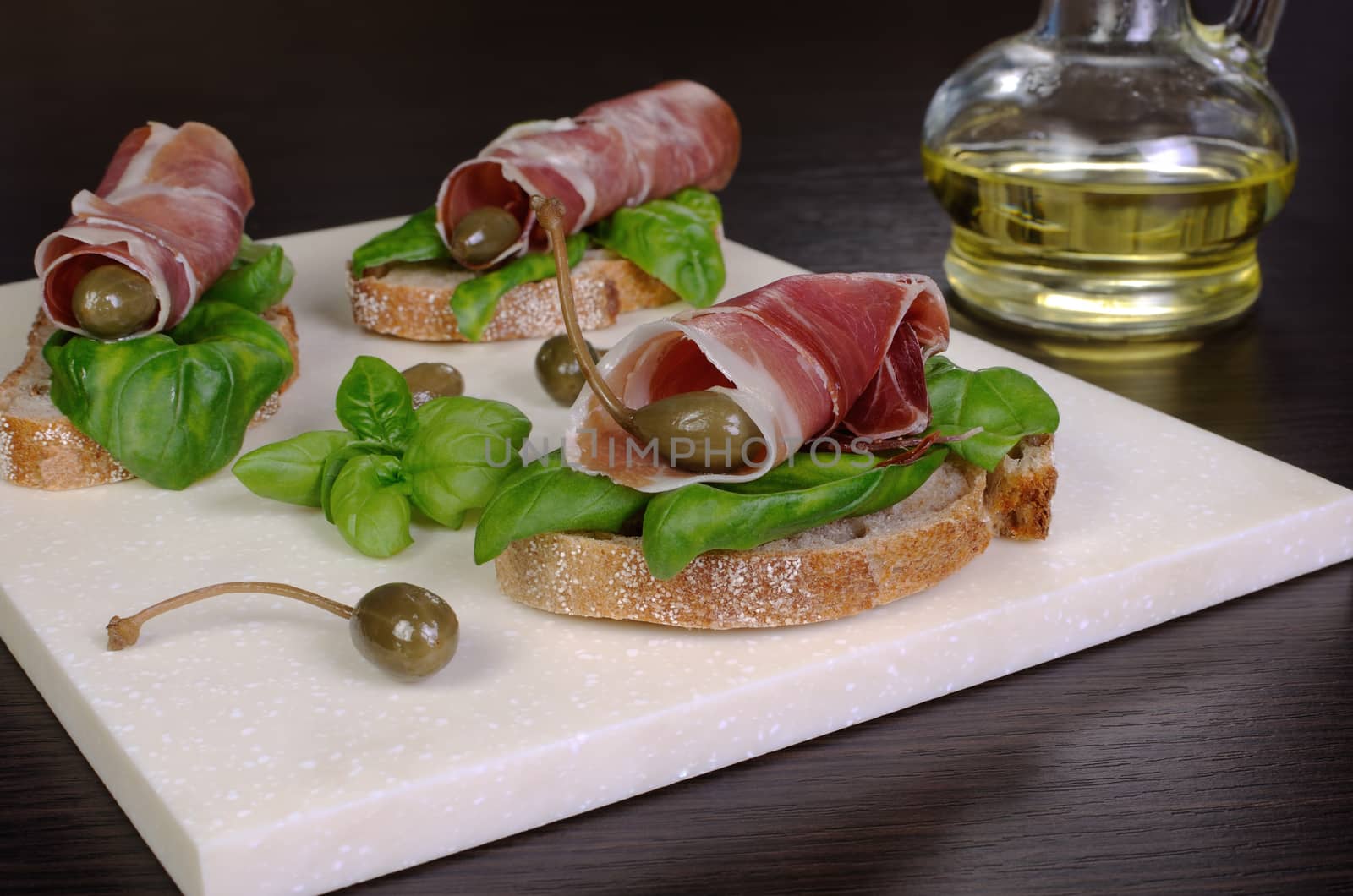 Slice Uncooked jerked pork ham jamon with capers and basil