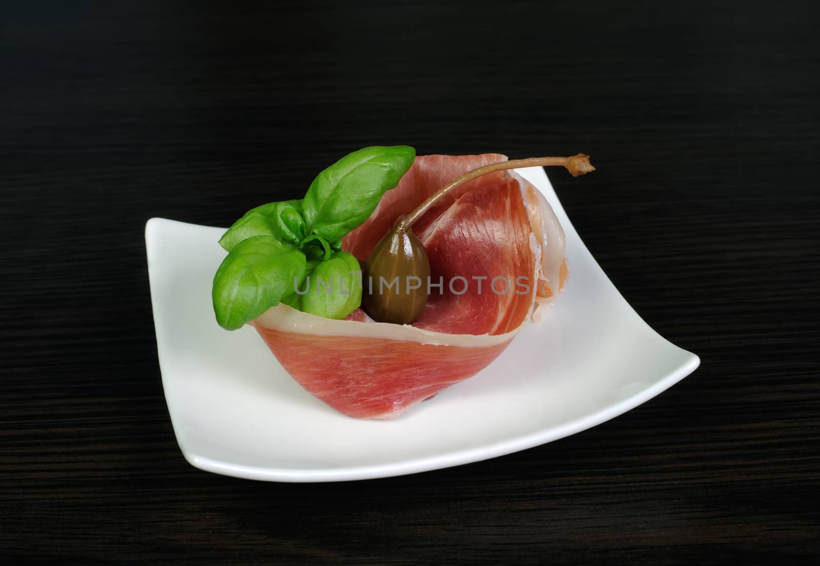 Slice Uncooked jerked pork ham jamon with capers and basil