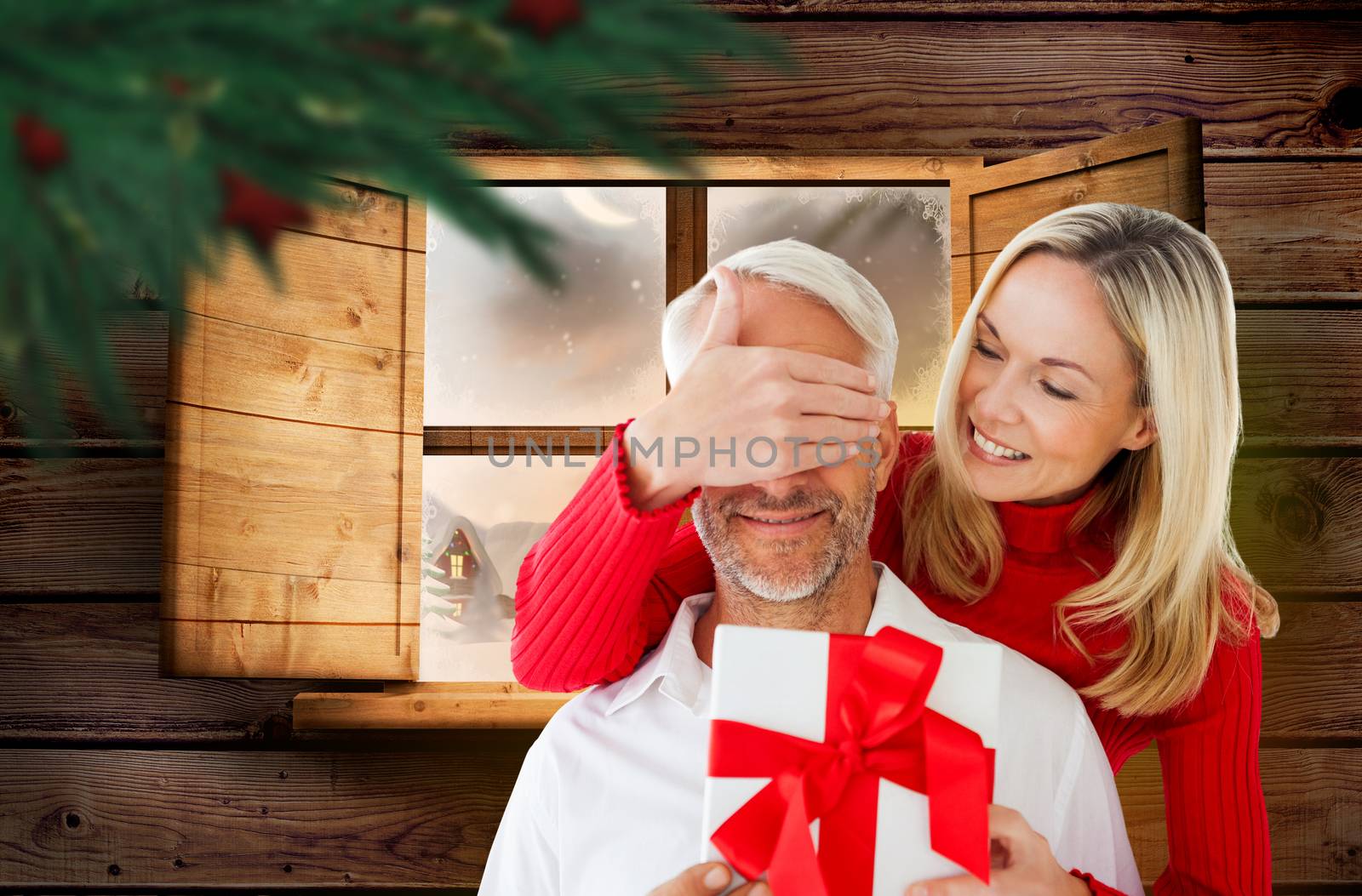 Loving couple with gift against festive fir branch with baubles 