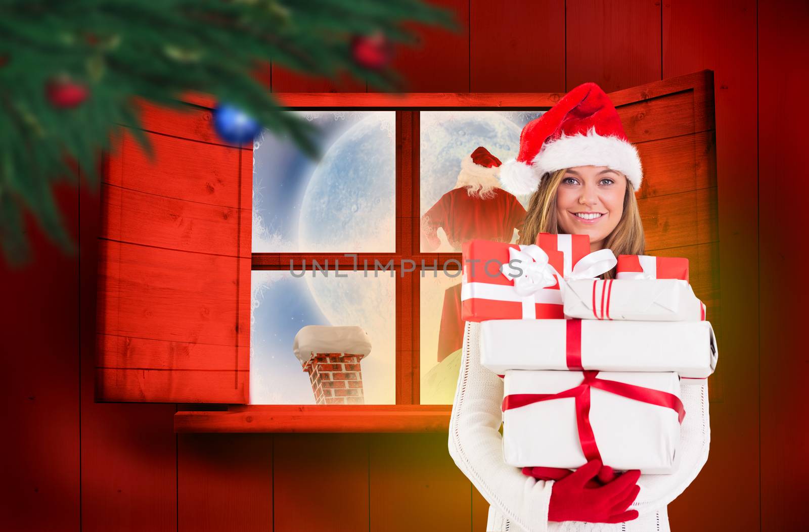 Festive blonde holding pile of gifts against festive fir branch with baubles 