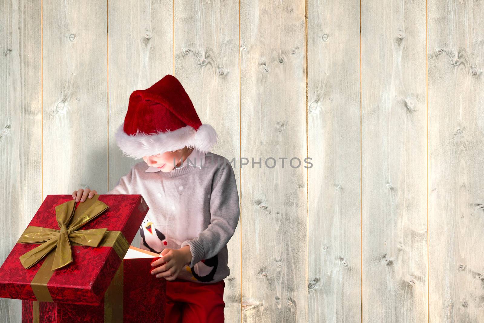 Festive boy opening gift against pale wooden planks