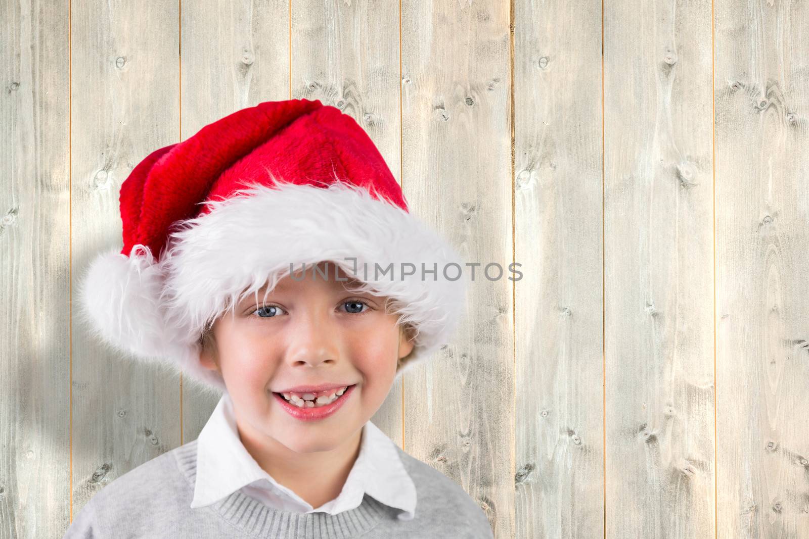 Festive boy smiling against pale wooden planks