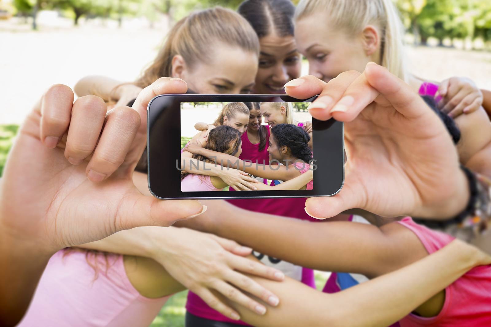 Composite image of hand holding smartphone showing photograph of breast cancer activists