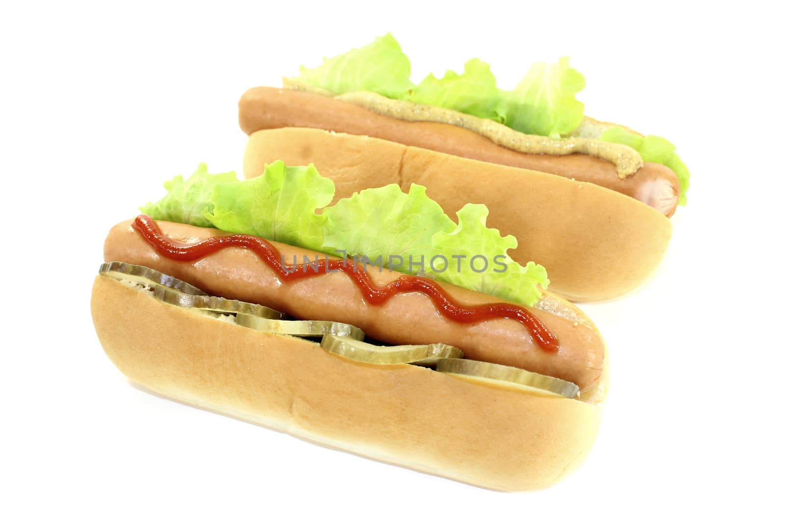 Hot dog with pickle, lettuce leaf, sausage, mustard and ketchup