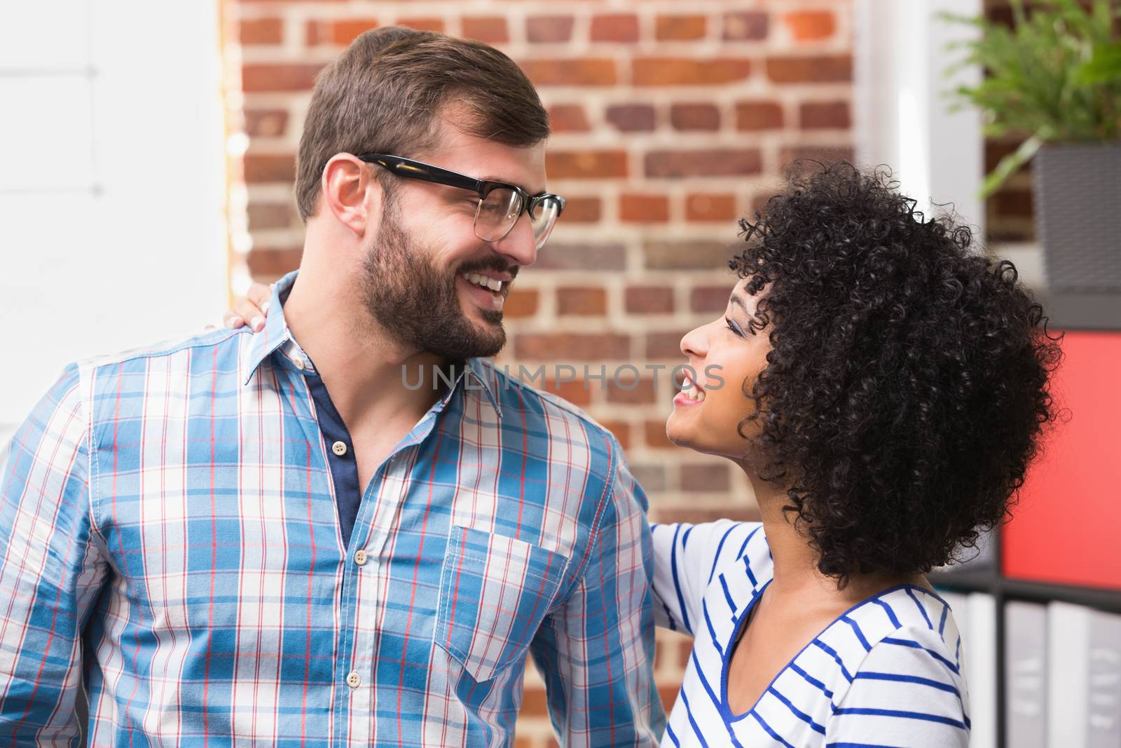 Young casual businessman and woman looking at each other in office