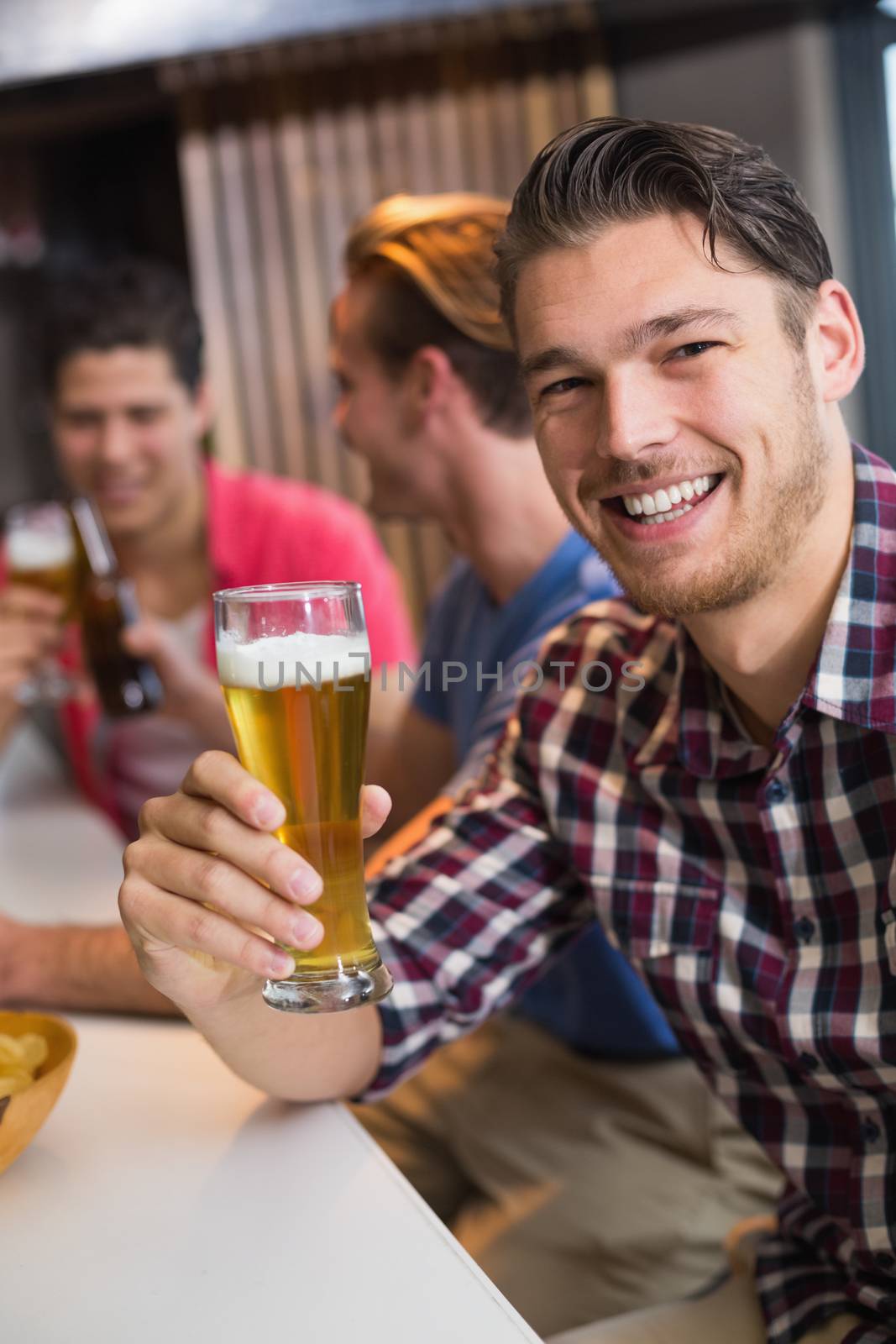 Young man holding pint of beer at the bar