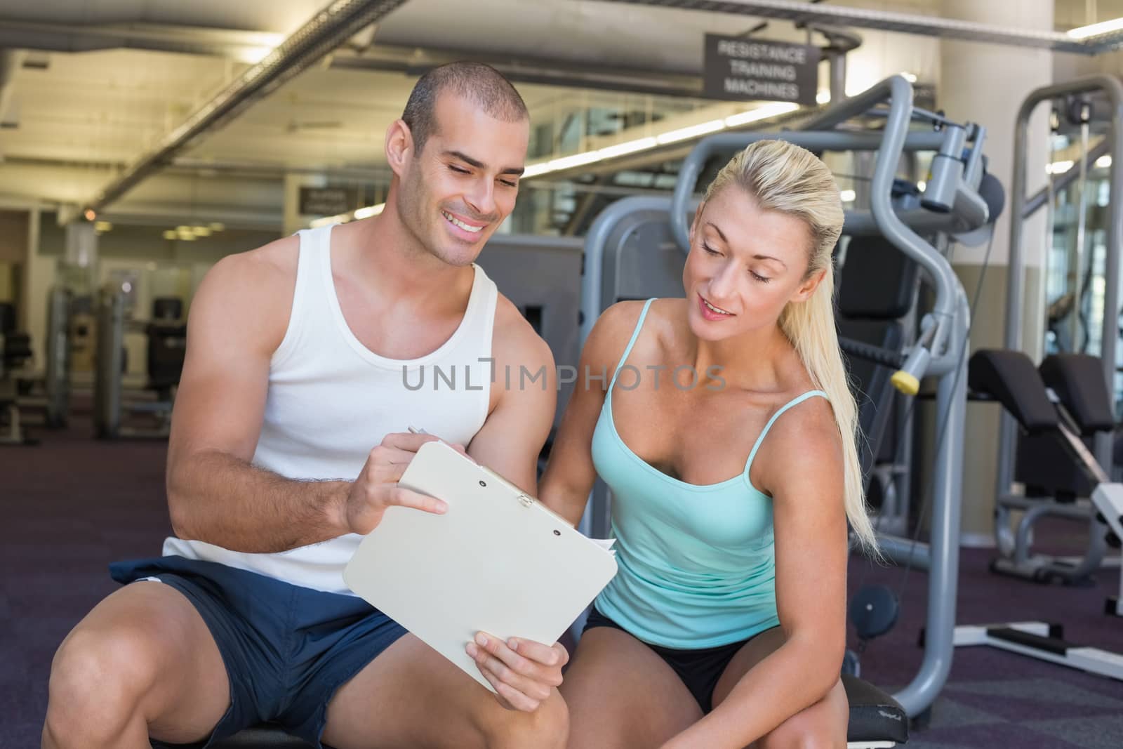 Woman discussing her performance on clipboard with trainer at gym by Wavebreakmedia