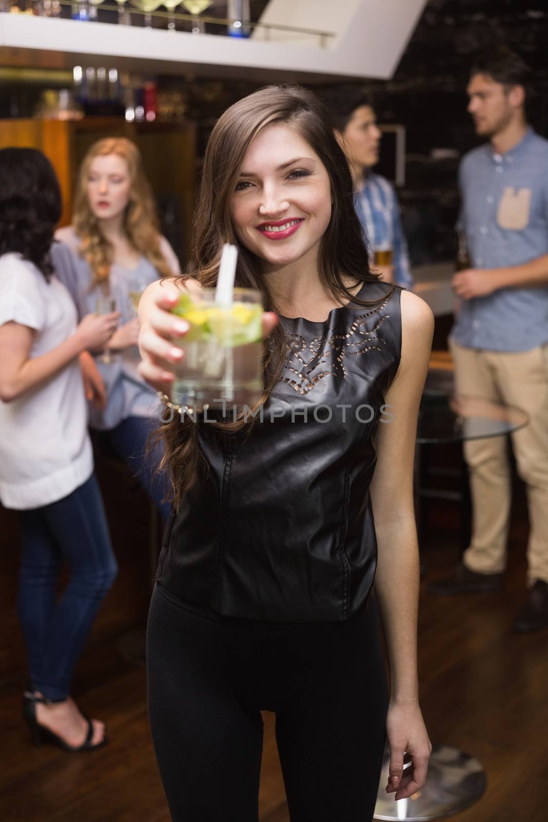 Pretty brunette holding a cocktail by Wavebreakmedia