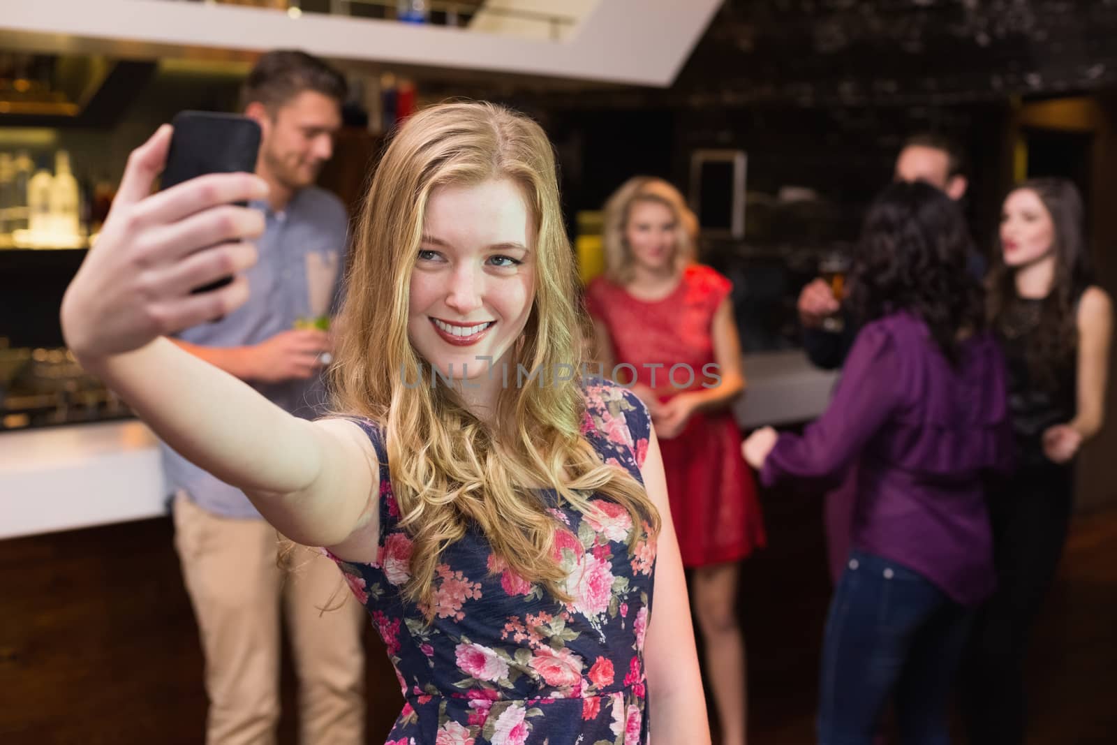 Pretty blonde taking a selfie at the bar