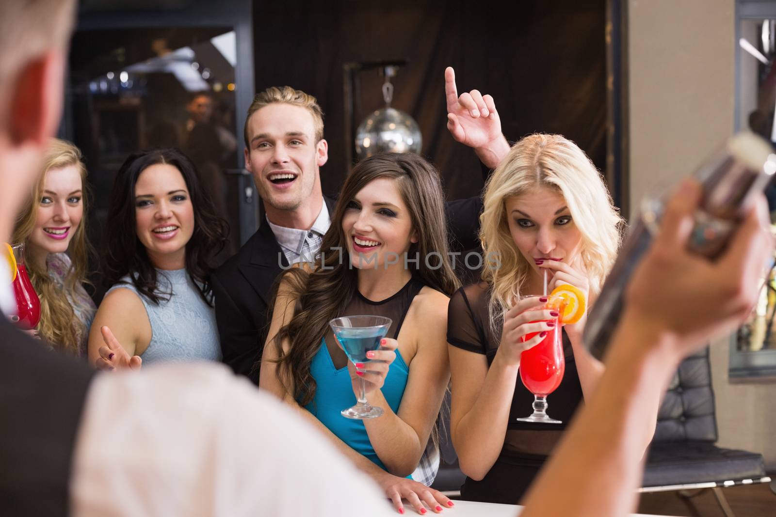 Attractive friends being served cocktails at the bar