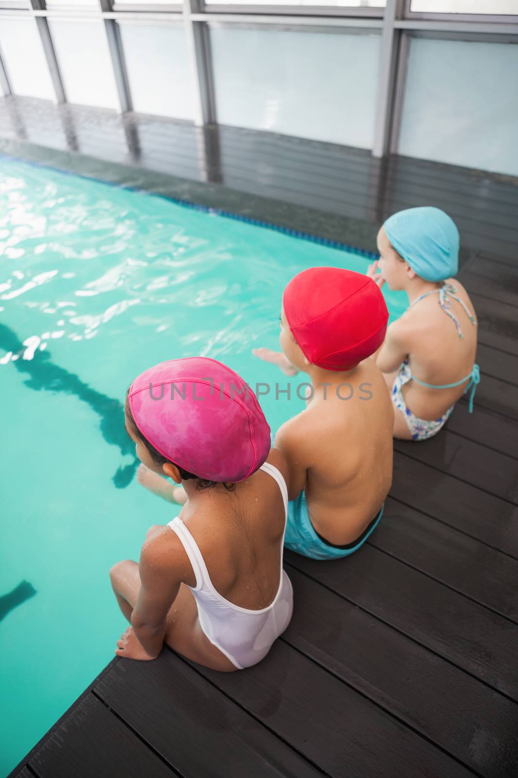 Cute swimming class sitting poolside by Wavebreakmedia