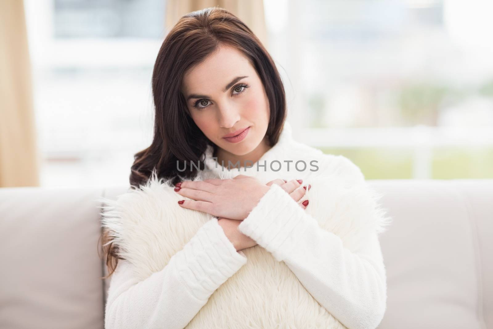 Beauty brunette holding a cushion on the couch at home