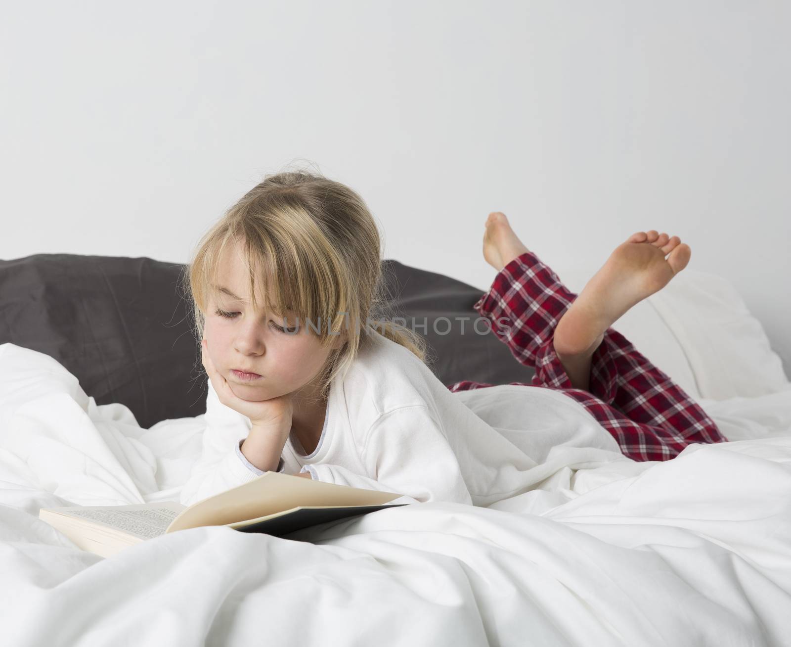 Young girl reading a book in bed