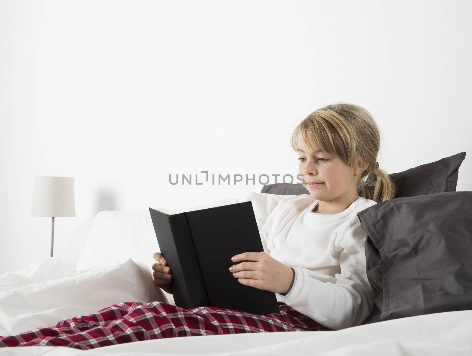 Young girl reading a book in bed