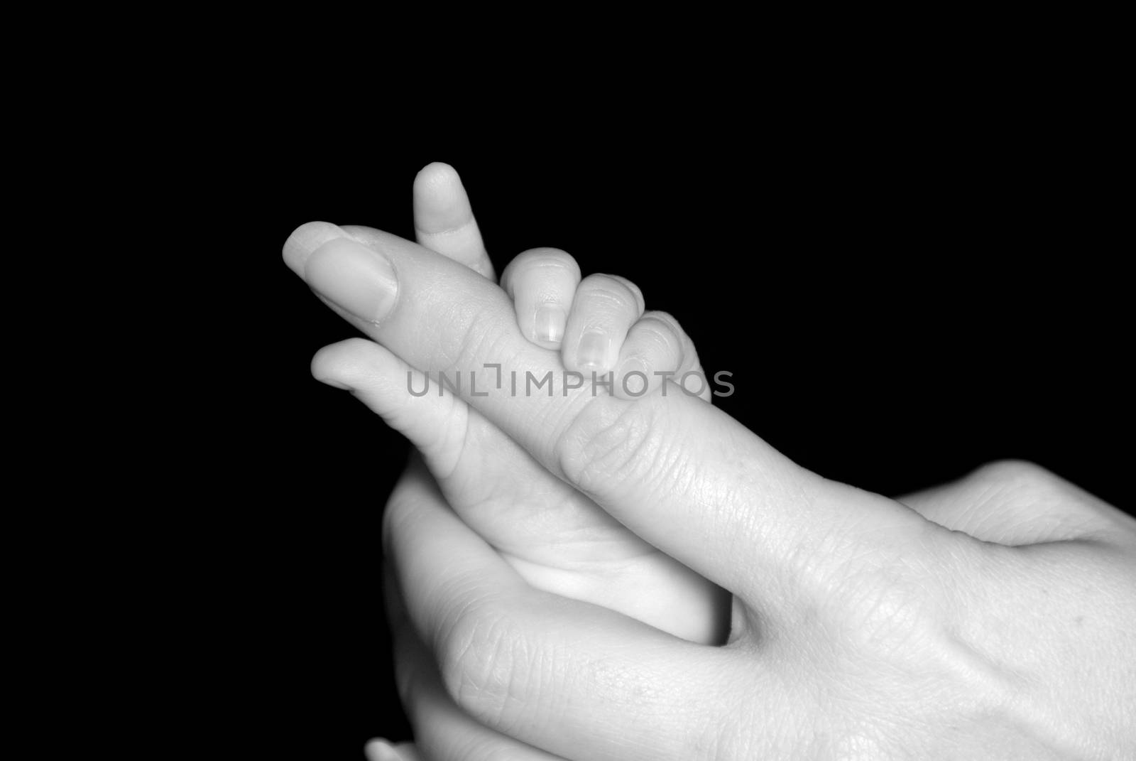 Five week old baby holding mothers finger.
