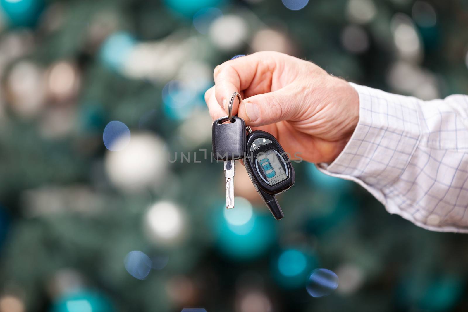 Male hand holding car key against Christmas background