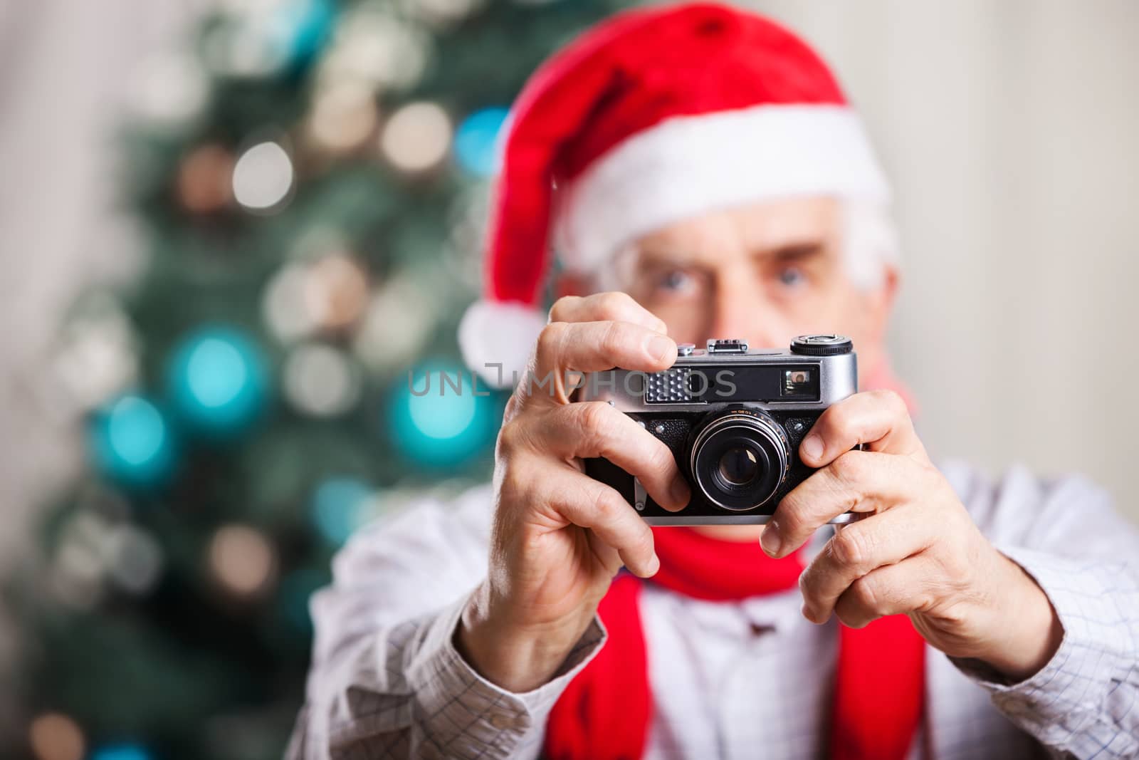 Senior man taking photo on Christmas background by photobac
