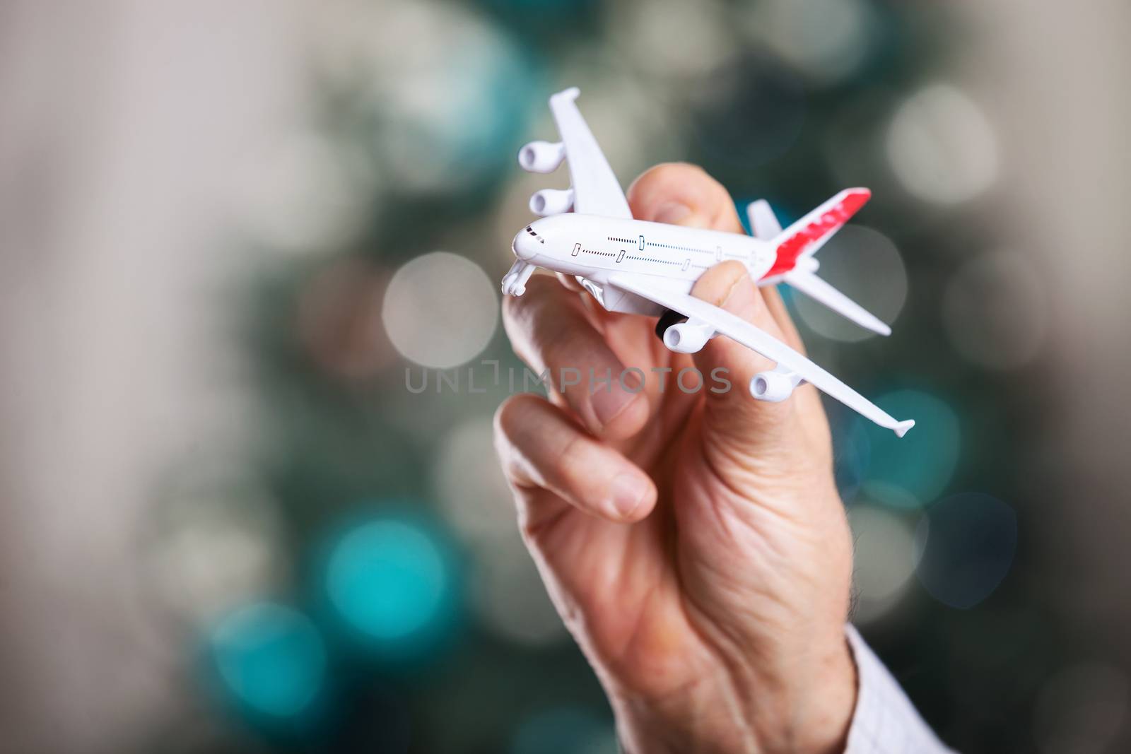Closeup of man hand holding model of airplane on a Christmas background