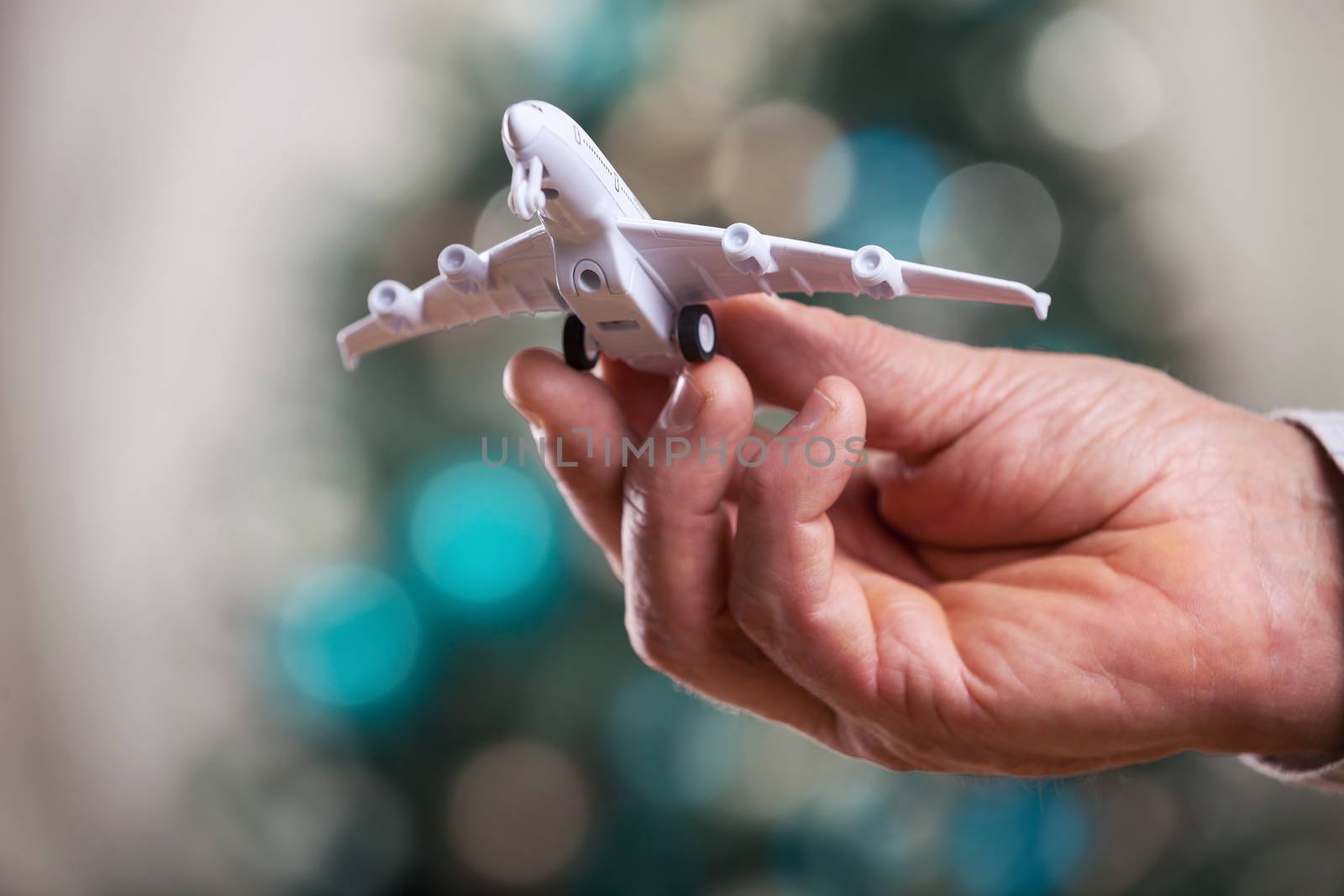 Closeup of man hand holding model of airplane on a Christmas background